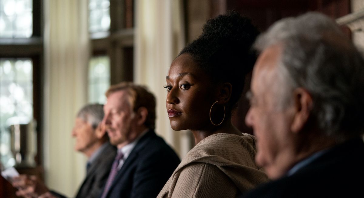 Nana Mensah come una giovane professoressa nera in una fila di uomini bianchi molto più anziani in The Chair di Netflix