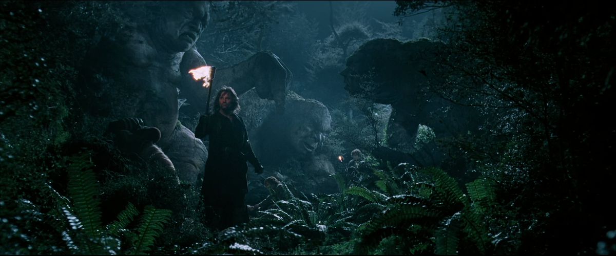 Aragorn tiene una torcia davanti a tre troll che sono stati congelati nella pietra ne La Compagnia dell'Anello. 
