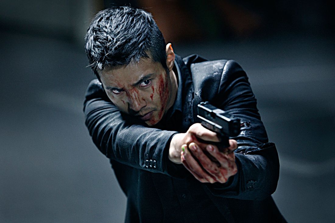 Un uomo vestito di nero (Won Bin) con il sangue sul viso e sulle mani allena il mirino di una pistola su un bersaglio fuori campo.