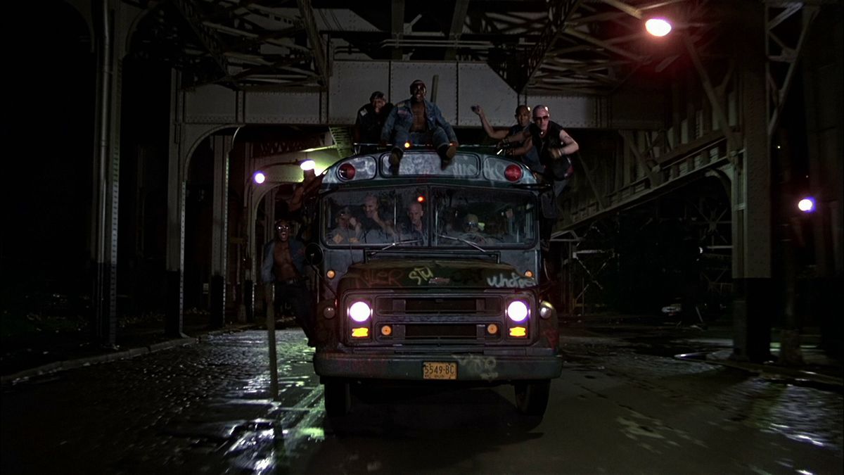 The Warriors ride and hang off of a bus on a bridge