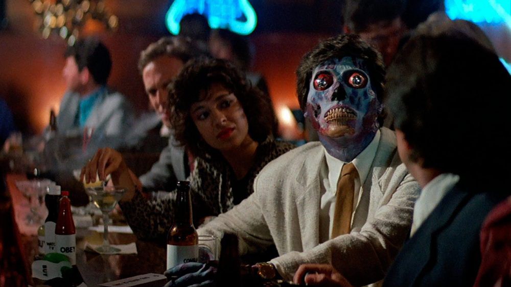 An alien peering up at a television in a bar in They Live (1988)