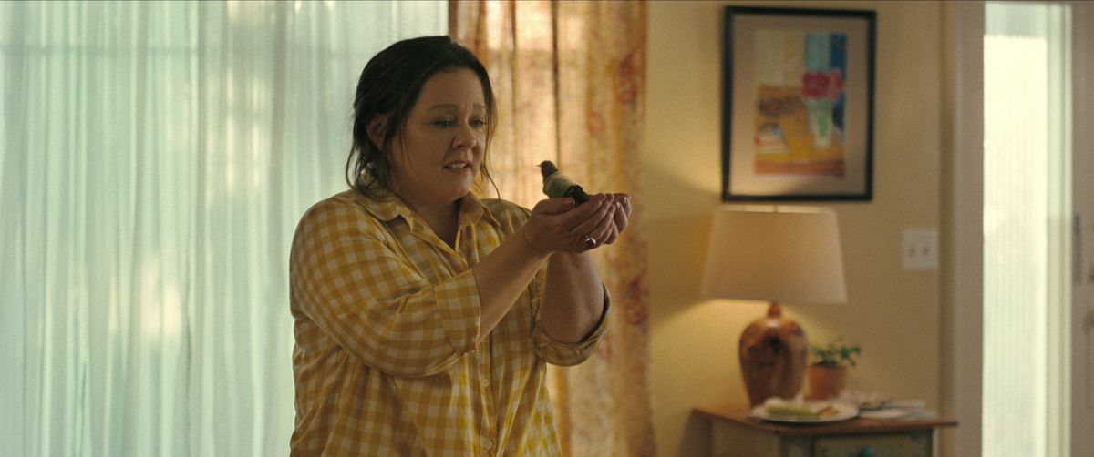 Melissa McCarthy holding a bird in her hands in The Starling