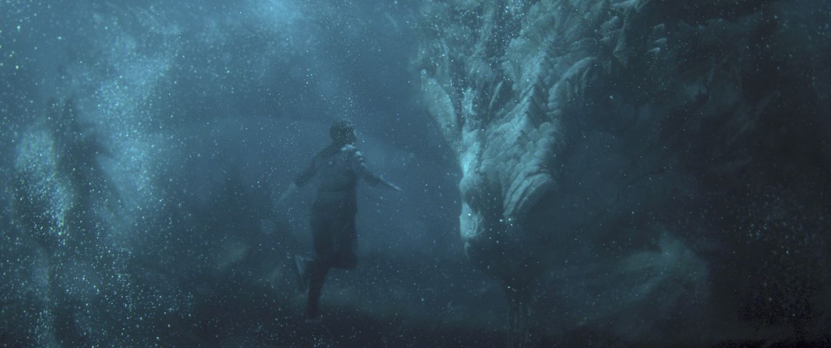 Shang-Chi (Simu Liu) galleggia sott'acqua di fronte a un enorme drago cinese, il Grande Protettore in Shang-Chi e la Leggenda dei Dieci Anelli. 