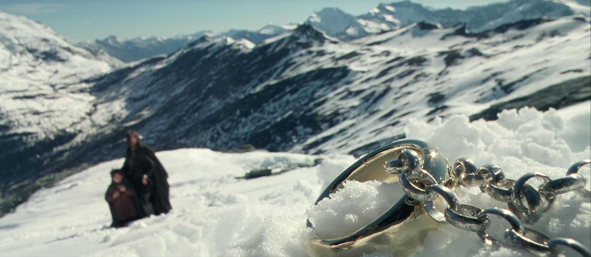 A close up of the One Ring on its bulky silver chain, lying in the snow, from The Fellowship of the Ring.