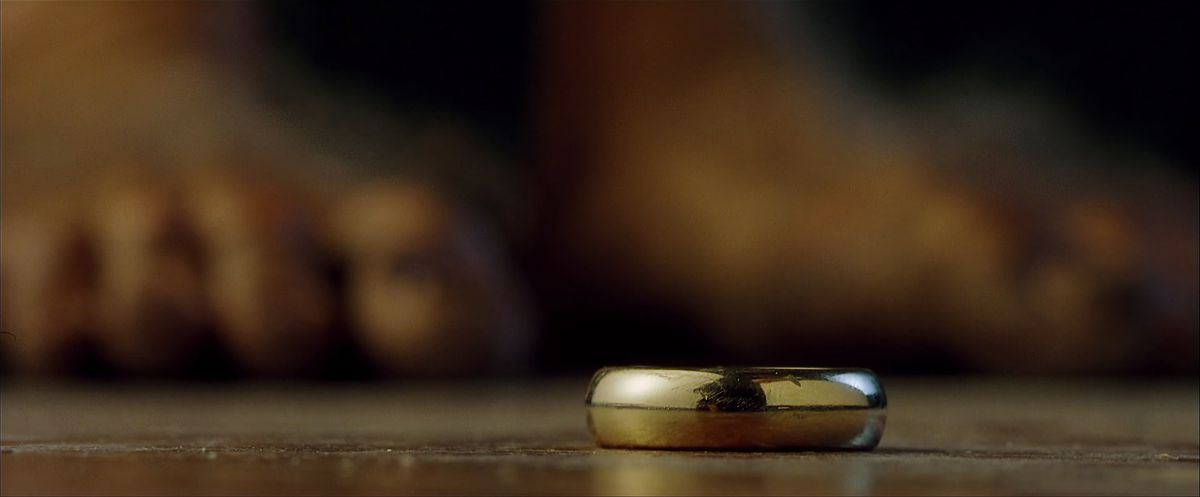 The One Ring lies on the floor of Bag End, Bilbo’s toes out of focus in the background in The Fellowship of the Ring. 