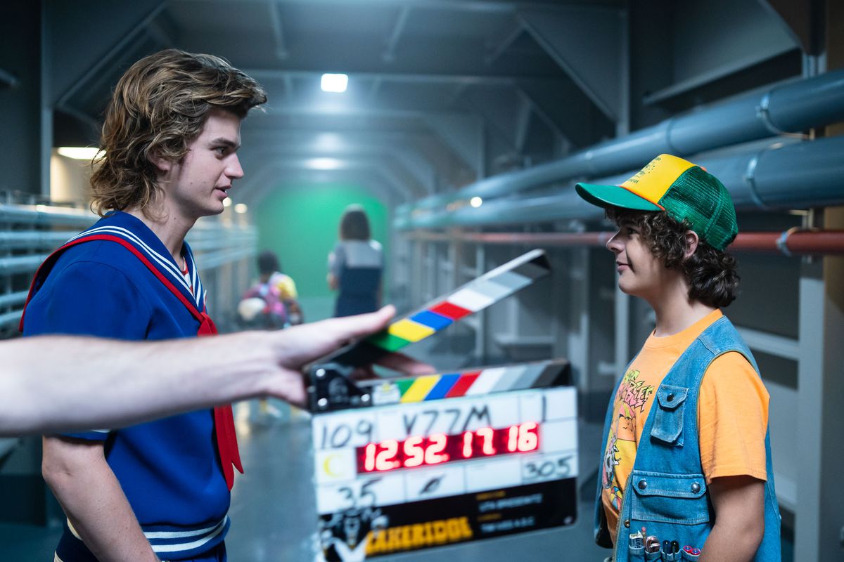 stranger things set photo with clapboard and two actors in an underground tunnel