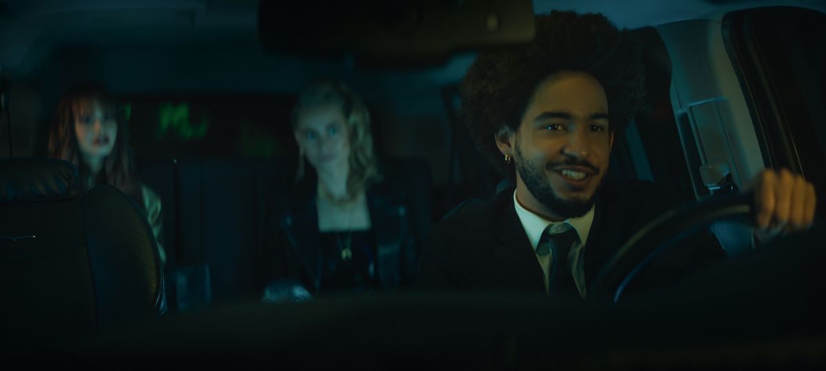 Benny (Jorge Lendeborg Jr.) è seduto al posto di guida con un sorriso strambo e due vampiri alle sue spalle in Night Teeth