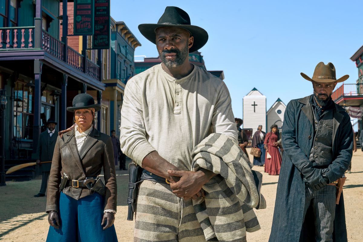 Regina King, Idris Elba e LaKeith Stanfield in abiti western, schierati lungo la strada di una città del vecchio West in The Harder They Fall.