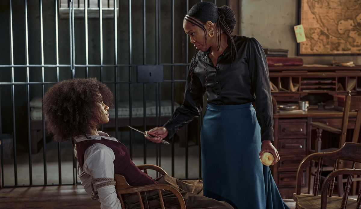 Regina King punta un coltello sulla faccia di Zazie Beetz mentre i due parlano nell'ufficio di uno sceriffo del Vecchio West con una cella dietro di loro in The Harder They Fall.