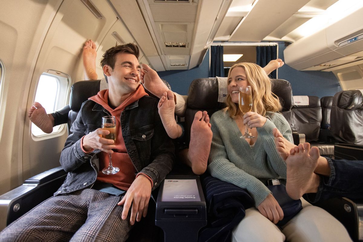 Cary and Brooke (Drew Tarver and Heléne Yorke,) on a plane surrounded by feet in The Other Two