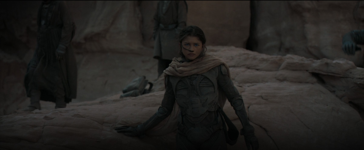 Inalan (Zendaya) si erge in penombra contro un affioramento di rocce in un'immagine tratta da Dune del 2021 di Denis Villeneuve