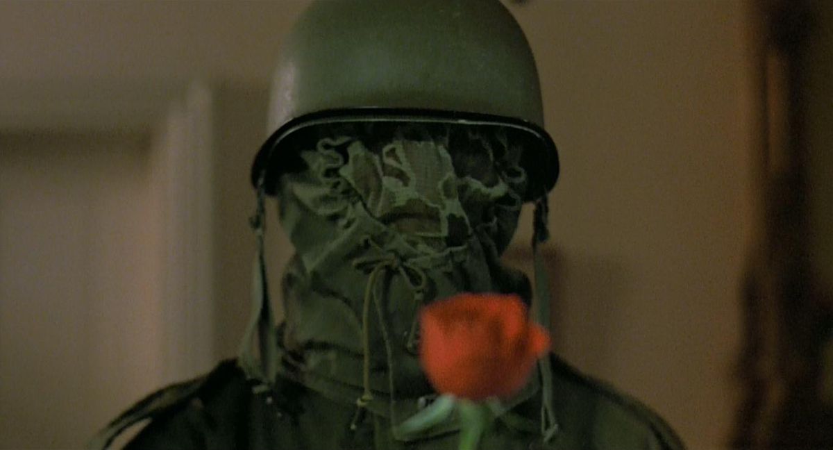 The Prowler (1981): the masked helmet man holds a rose