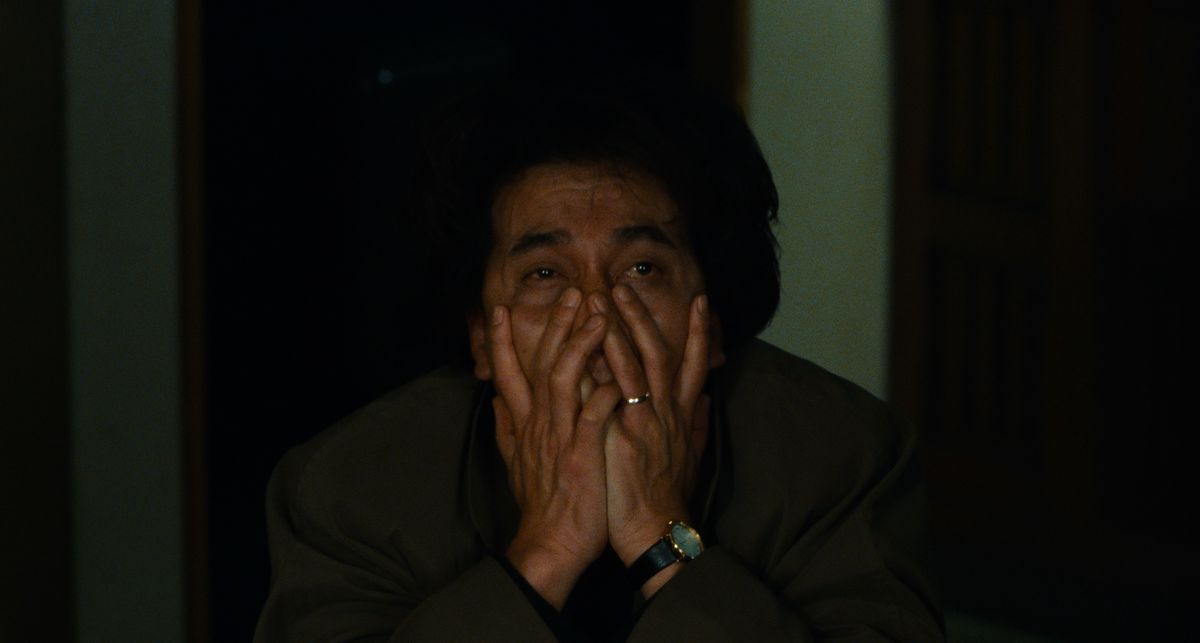 Il detective Takabe (Kôji Yakusho) si incrocia le mani sul viso per la stanchezza e l'orrore in Cure (1997)