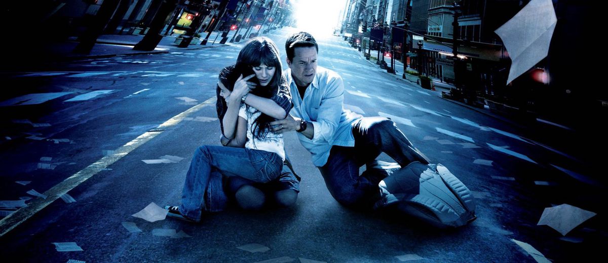 Zoe Deschanel and Mark Wahlburg huddle together around Ashlyn Sanchez in the middle of a deserted, windblown city street in a stylized promotional image for M. Night Shyamalan’s The Happening