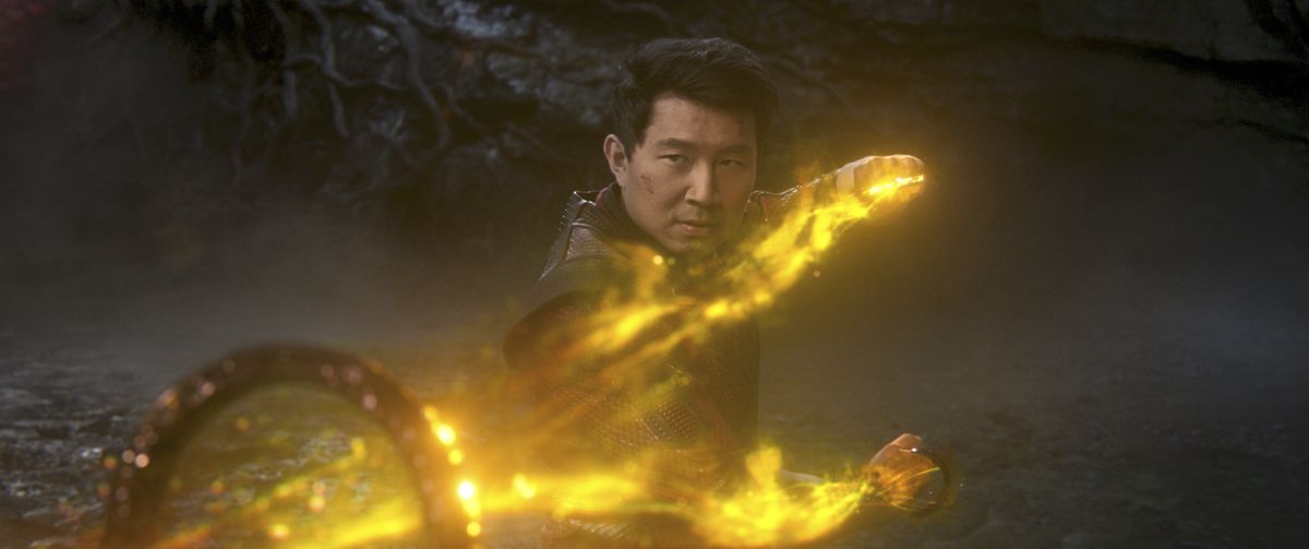 Simu Liu brandisce i Dieci Anelli, circondato dal fuoco giallo, come Shang-Chi in Shang-Chi e la Leggenda dei Dieci Anelli.