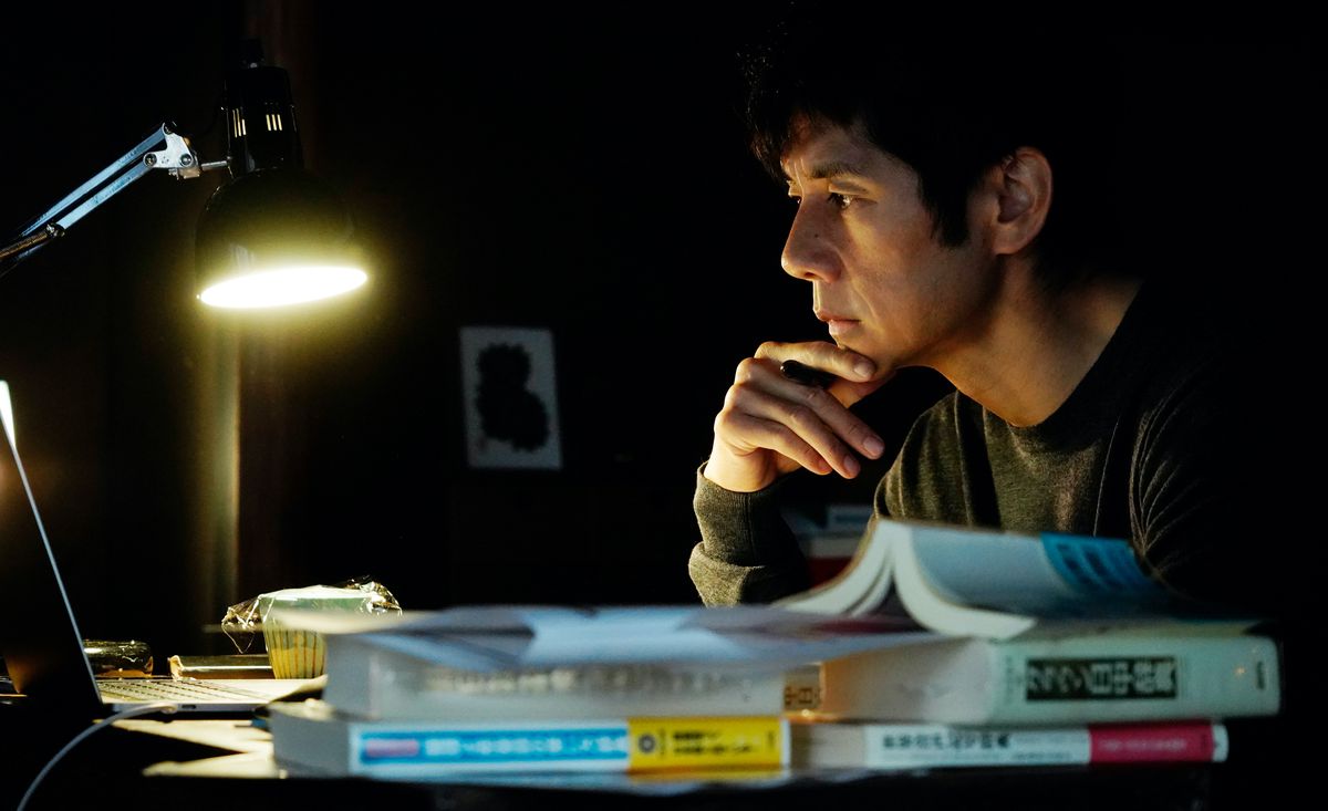 Hidetoshi Nishijima sits at his desk in a dark room in Drive My Car