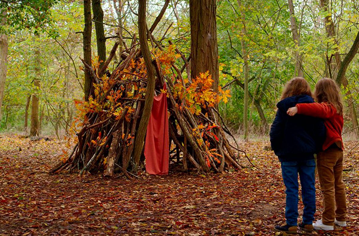 Due giovani ragazze abbracciate contemplano il loro forte bastone nella foresta a Petite Maman