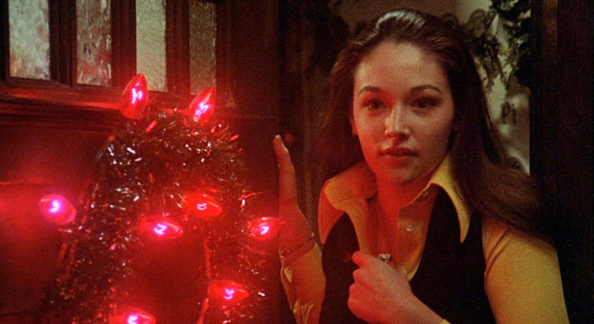 Olivia Hussey è in piedi accanto a una ghirlanda natalizia rosso vivo in Black Christmas.