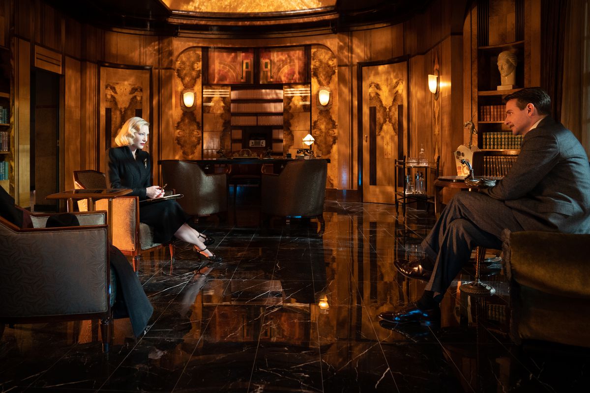 Stan Carlisle siede nell'ufficio art déco della dottoressa Lillith Ritter in Nightmare Alley di Guillermo del Toro.