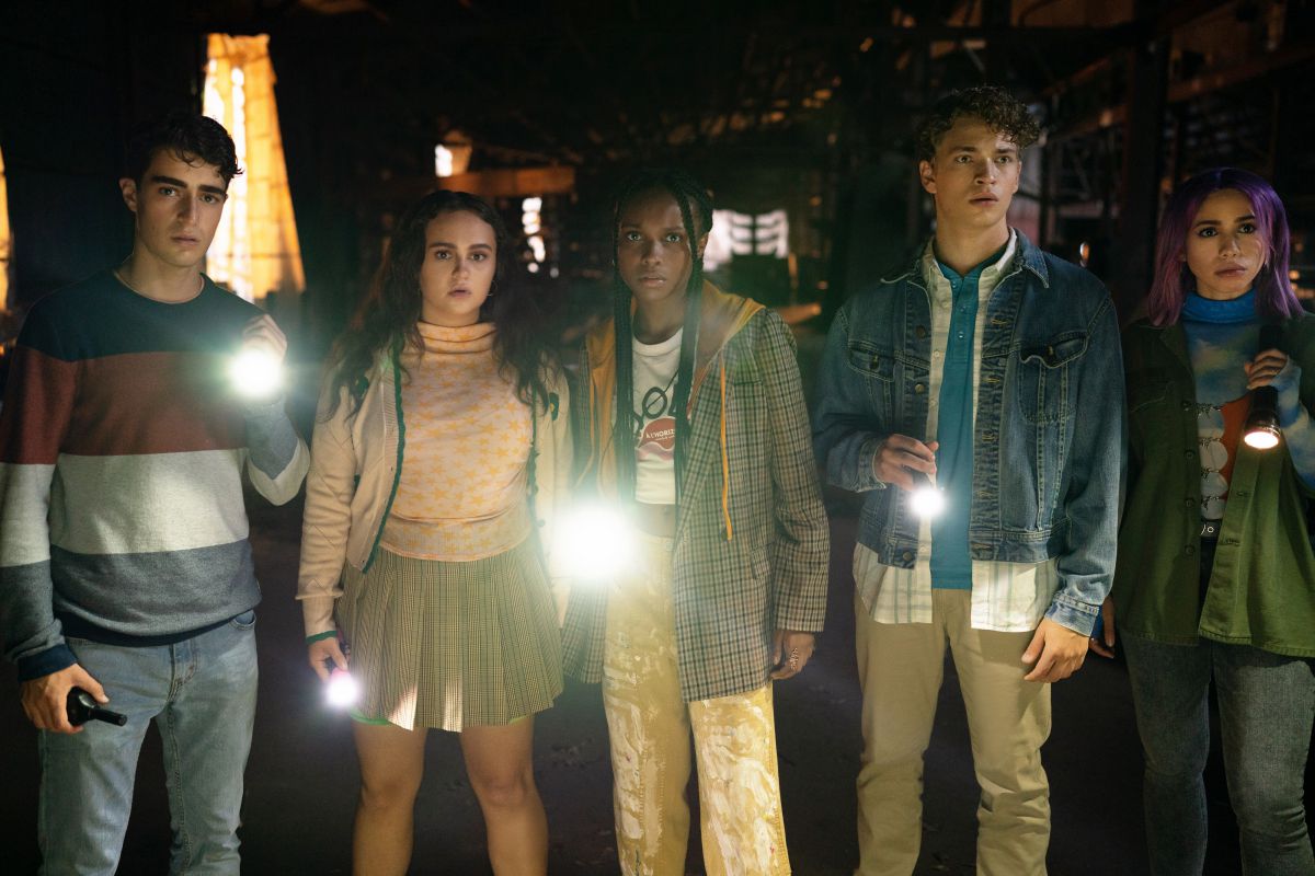 Naomi e la sua banda di risolutori di misteri Scooby-Doo, che tengono in mano torce di notte e sembrano spaventati
