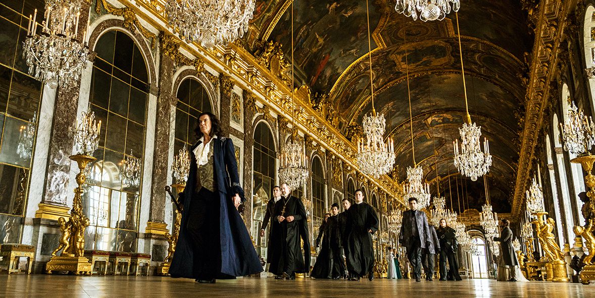 Pierce Brosnan nei panni di Luigi XIV attraversa Versailles, circondato da dorature e lampadari