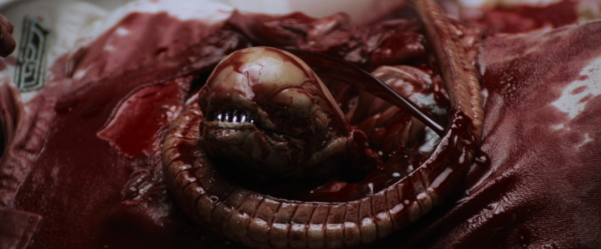 Uno xenomorfo che si srotola dal petto di Kane in Alien (1979).