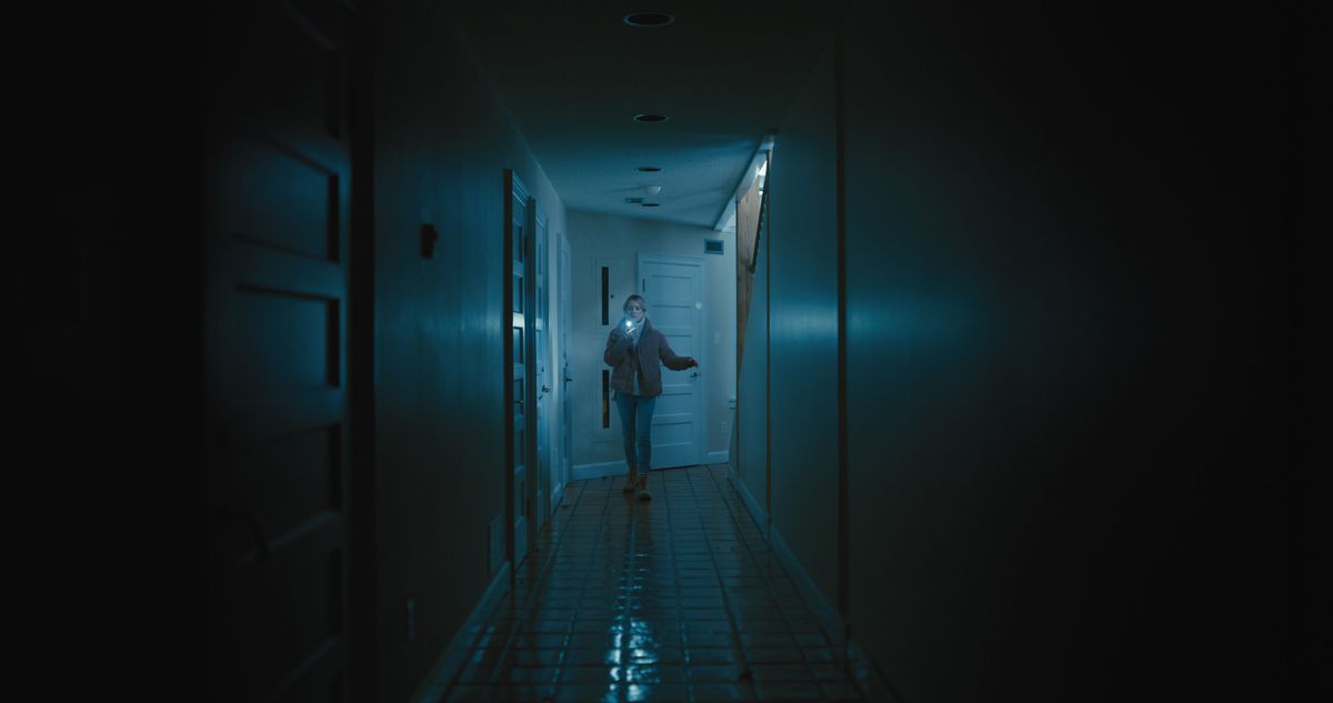 Sophie cammina lungo un corridoio lungo e buio, illuminato dal suo telefono, in See For Me