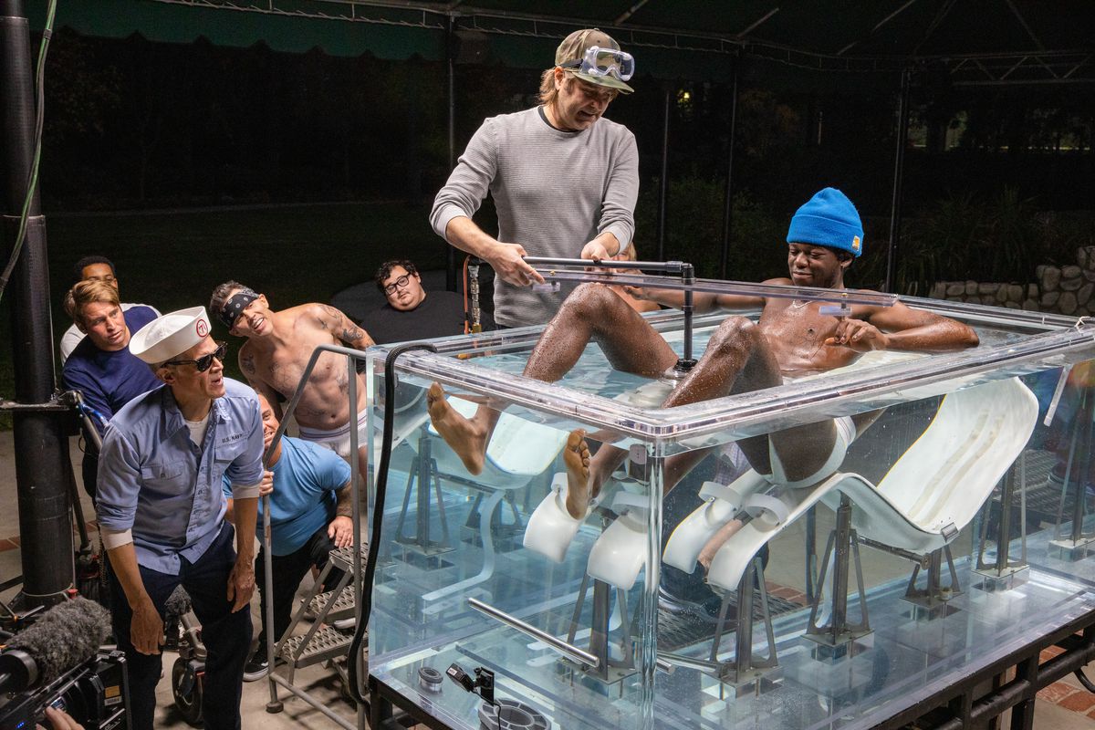 Un gruppo di membri di Jackass sta attorno a una vasca piena d'acqua mentre organizzano un'acrobazia