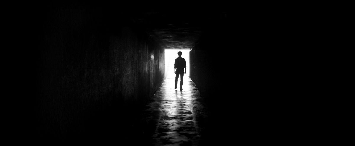 Una silhouette di una figura in un corridoio, con la luce che brilla dietro per dare l'aspetto di un'ombra.