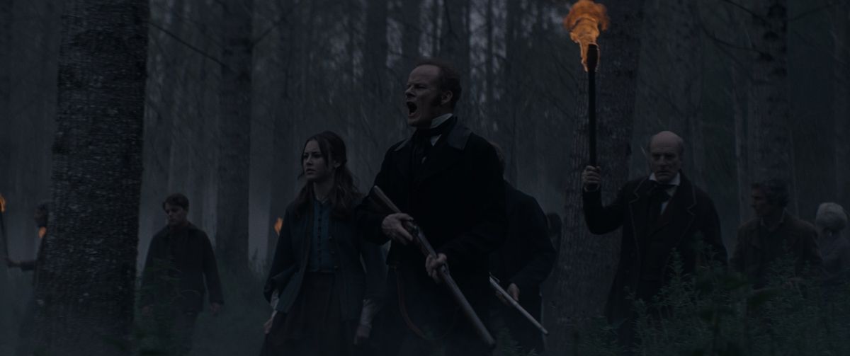 Alistair Petrie e un gruppo di altri uomini con i fucili danno la caccia a un mostro attraverso i boschi oscuri in The Cursed