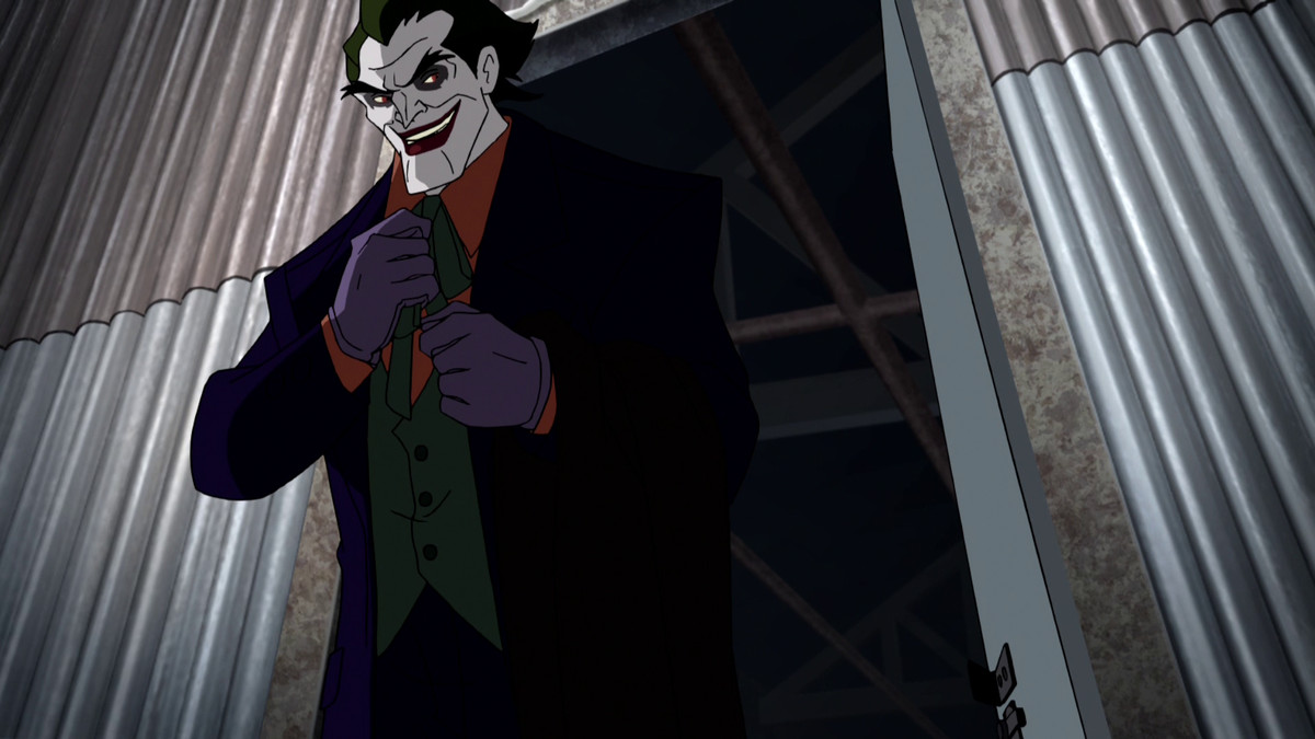 Il Joker, che indossa una giacca viola sopra un gilet verde e una maglietta arancione con guanti viola, si aggiusta la cravatta mentre lascia un edificio di metallo.