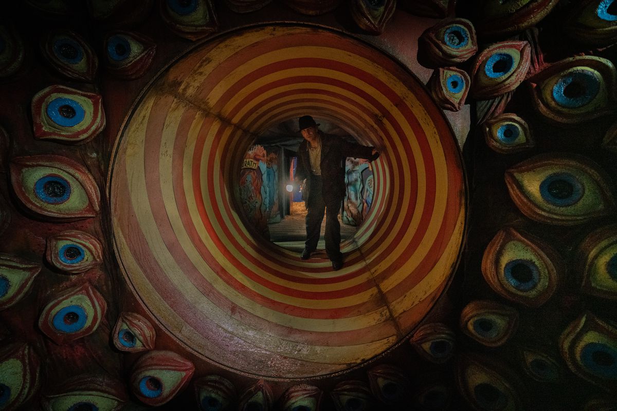 Bradley Cooper nei panni di Stan Carlisle in un tunnel della casa dei divertimenti circondato da occhi in Nightmare Alley di Guillermo del Toro.