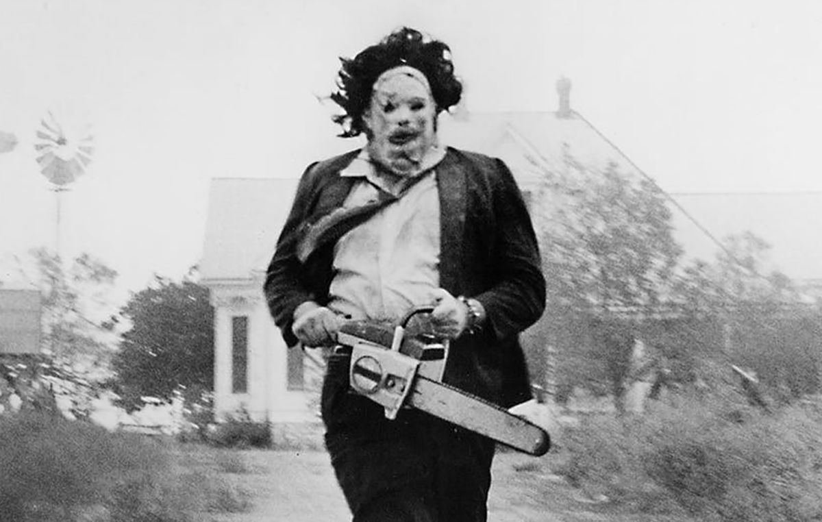 Leatherface, motosega in mano, che corre lungo la strada nel massacro della sega a catena originale del Texas del 1974
