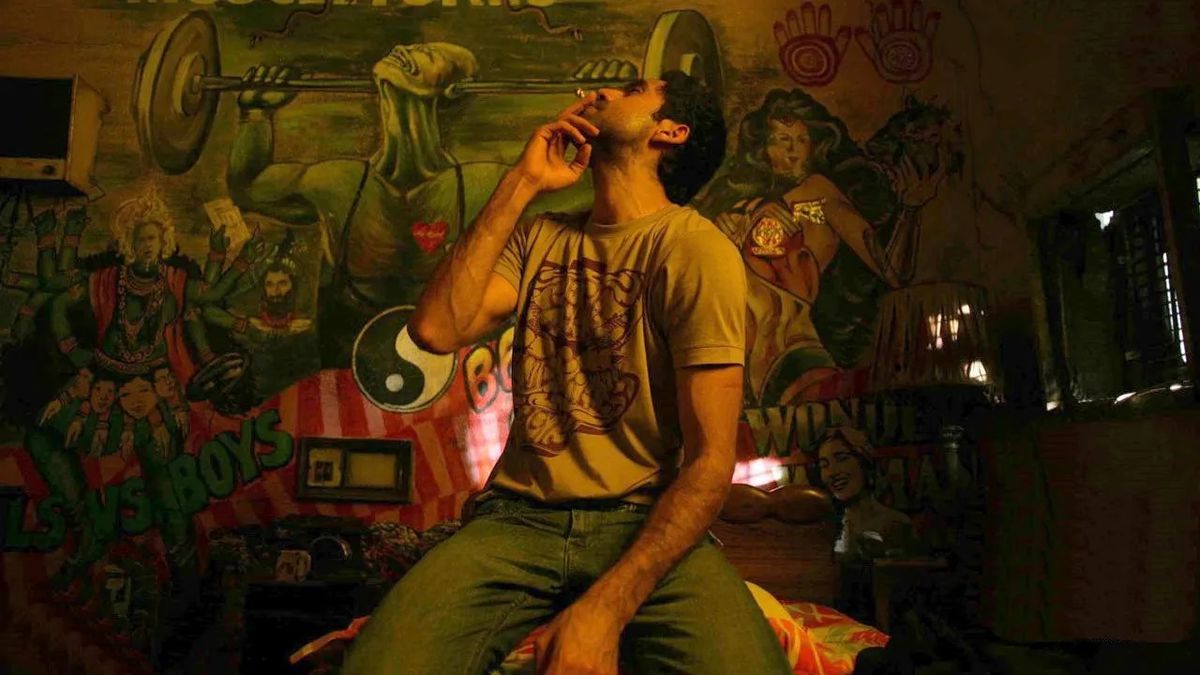Dev (Abhay Deol) fuma una sigaretta in una stanza piena di graffiti in Dev.D.