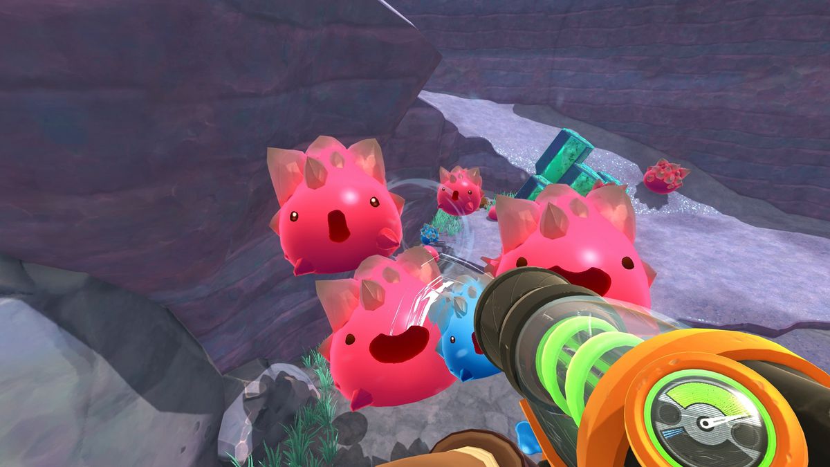 Un gruppo di melme sferiche rosa che vengono risucchiate da una pistola in un allevatore di melma