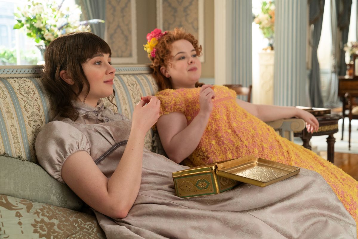 Eloise seduta sul divano a godersi dei cioccolatini con la sua amica Penelope