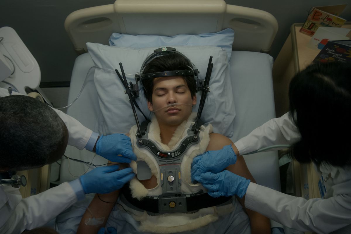 Un personaggio Cobra Kai sdraiato a letto con un tutore per il collo mentre i medici lavorano su di lui