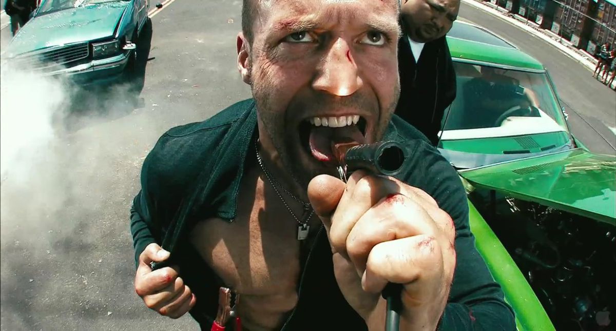 Jason Statham nei panni di Chev Chelios che si stringe la lingua e il capezzolo destro con i cavi jumper in Crank.