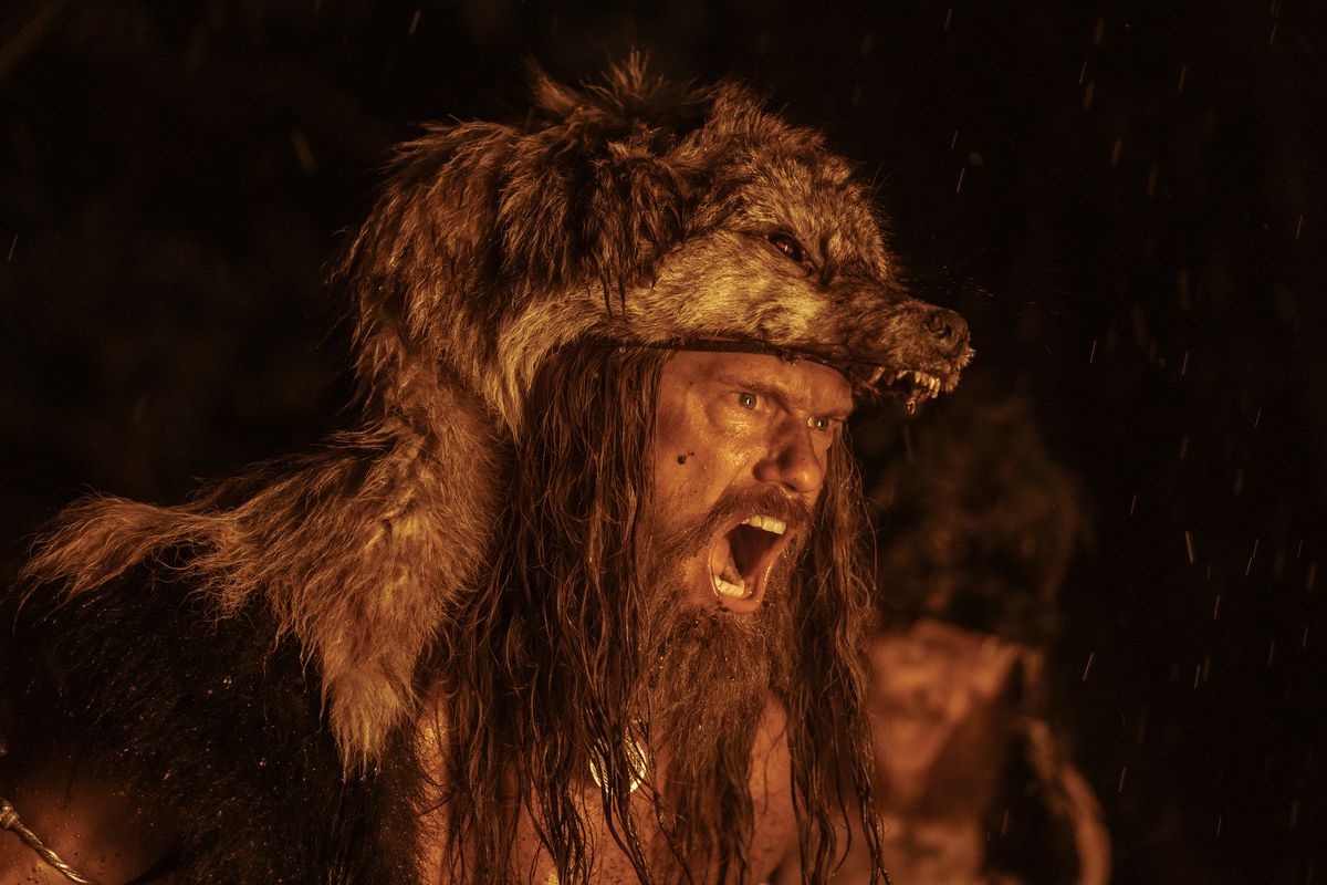 Alexander Skarsgard, che indossa una pelle di lupo, ulula durante un rituale di guerra a lume di fuoco in The Northman
