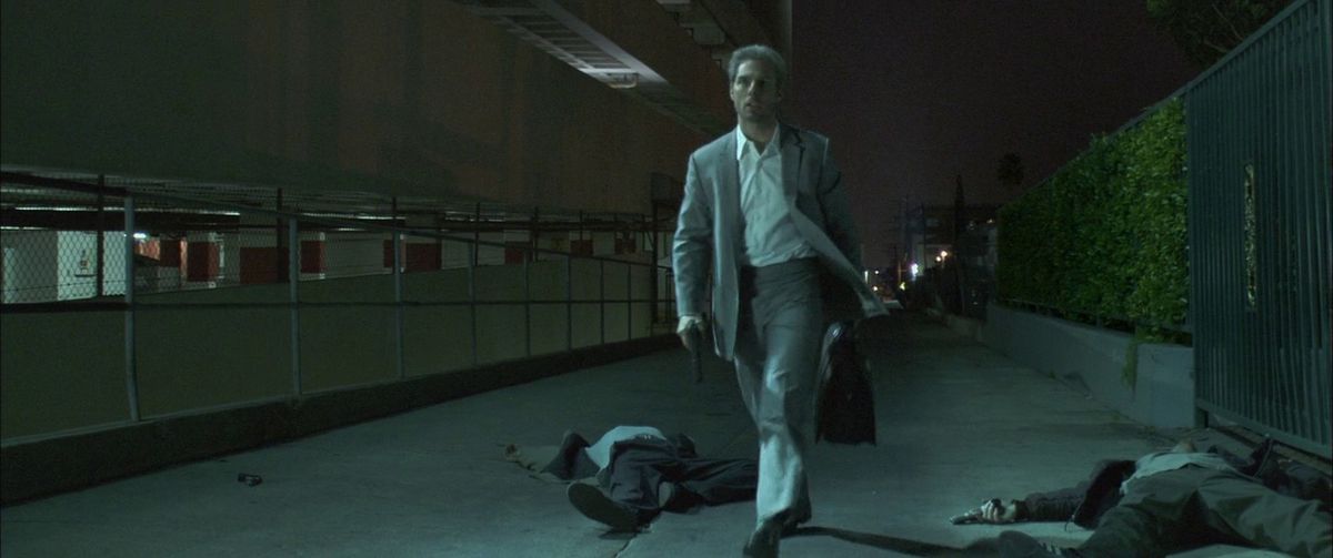 Tom Cruise, con in mano una pistola e una borsa, passa davanti ad alcuni cadaveri dopo alcuni omicidi a Collateral.