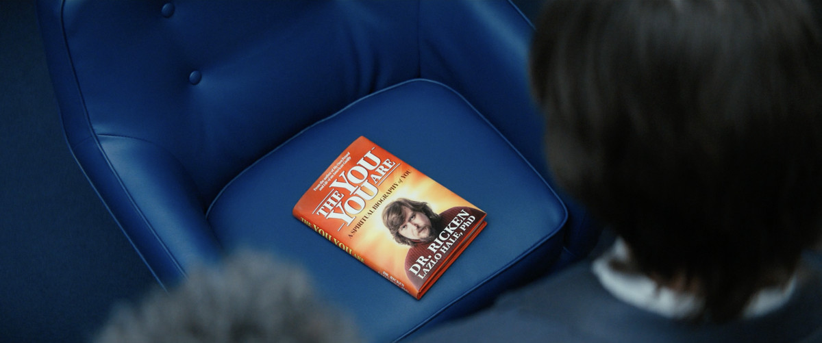 Il libro di Ricken seduto su una sedia blu con le schegge di Lumon che ci guardano dall'alto