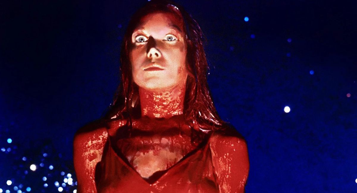 Sissy Spacek nei panni di Carrie che guarda in basso con un abito da ballo ricoperto di sangue di maiale in Carrie.
