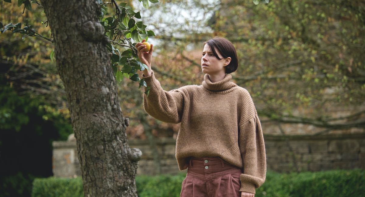Jessie Buckley raccoglie una mela altamente simbolica da un albero in Men di Alex Garland.