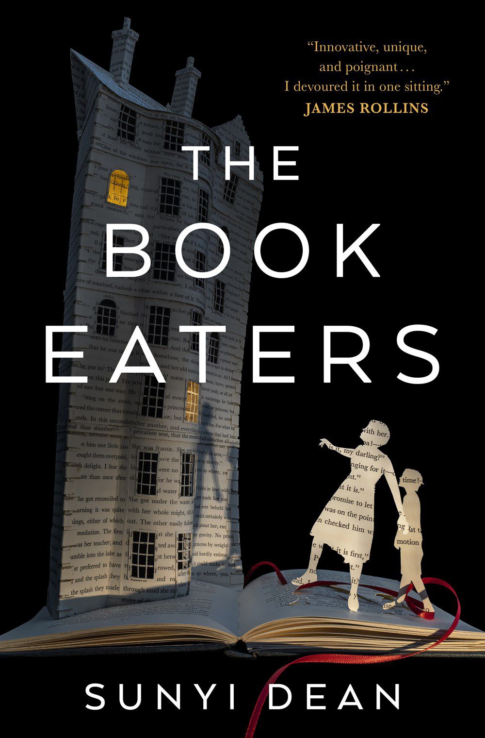 Immagine di copertina di The Book Eaters di Sunyi Dean, con l'immagine del diorama di un genitore, un figlio e una casa, tutti fatti di pagine di un libro, mentre sono in piedi su un libro.