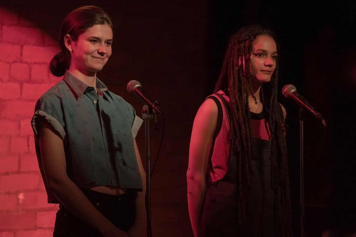 Frances e Bobbi in piedi sul palco davanti ai microfoni con una luce rossa