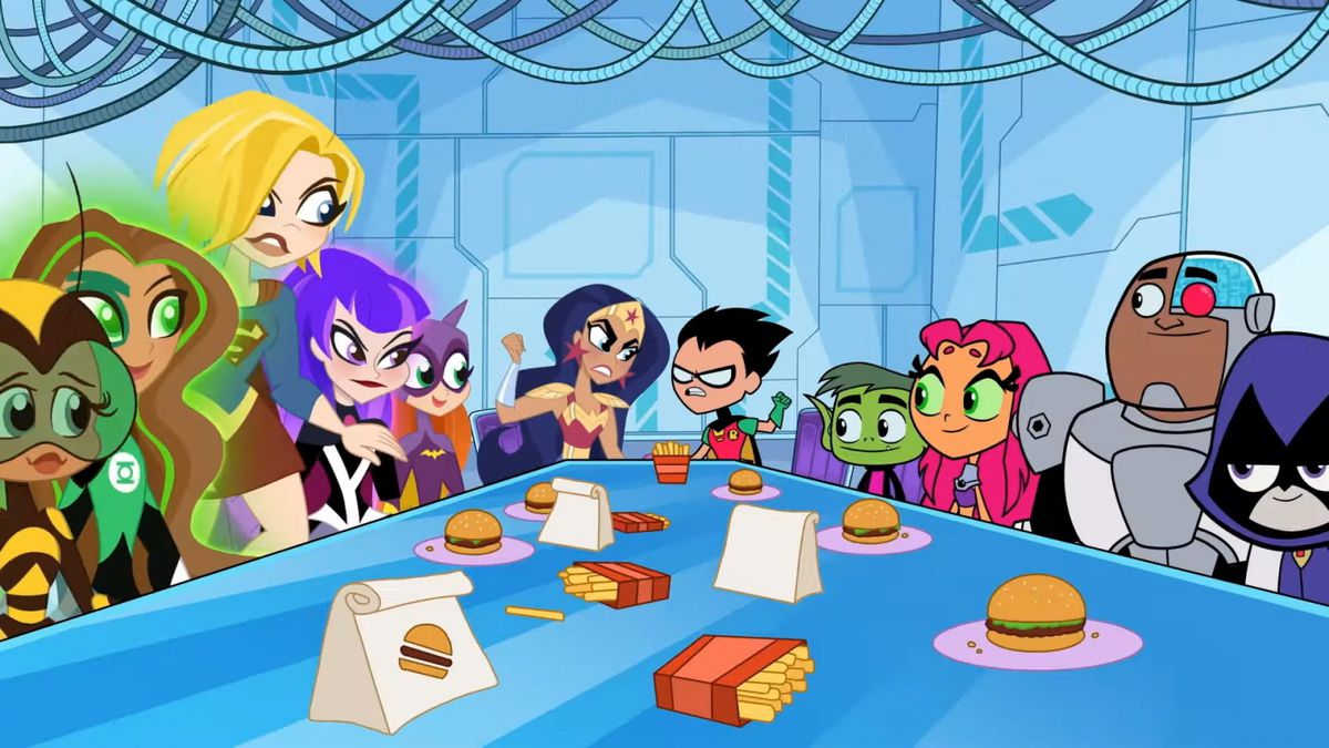 I Teen Titans e le DC Super Hero Girls siedono attorno a un tavolo con hamburger e patatine fritte.