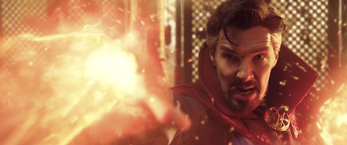 Benedict Cumberbatch nei panni del Dottor Strange fa esplodere fogli di luminescente cenere arancione dalle sue mani in Doctor Strange in the Multiverse of Madness.