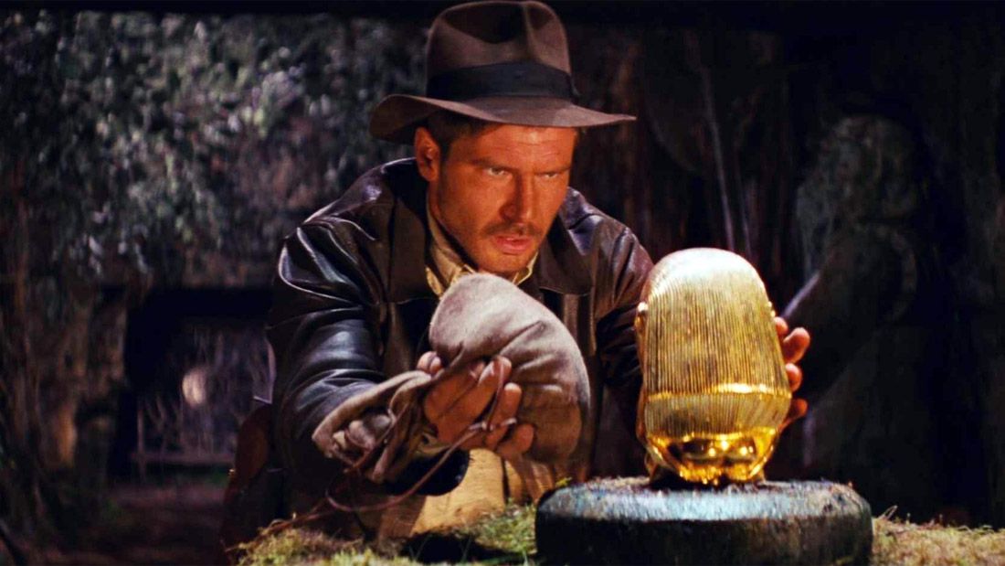 Harrison Ford nei panni di Indiana Jones che rimuove un artefatto da un piedistallo in I predatori dell'arca perduta