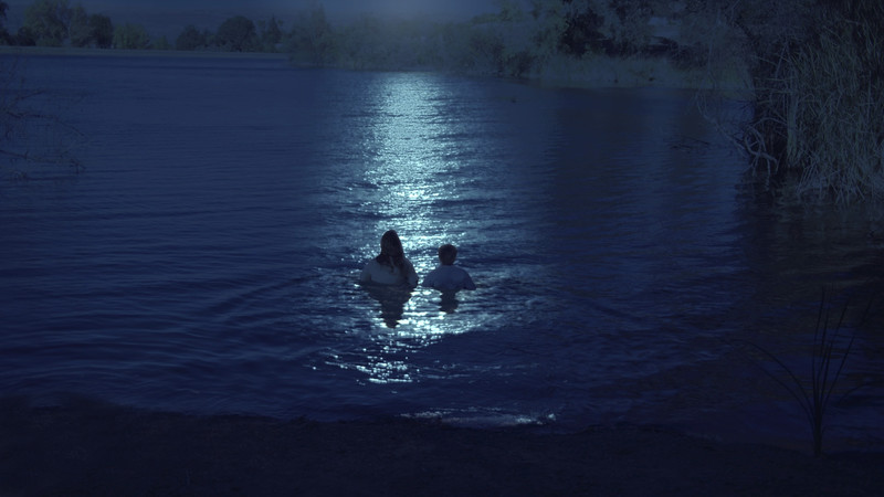 Due figure entrano in un lago al chiaro di luna