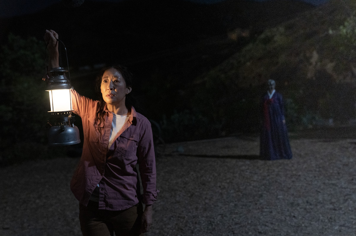 Sandra Oh nei panni di Beth che tiene una lanterna all'esterno mentre una figura inquietante si trova dietro di loro a Umma.